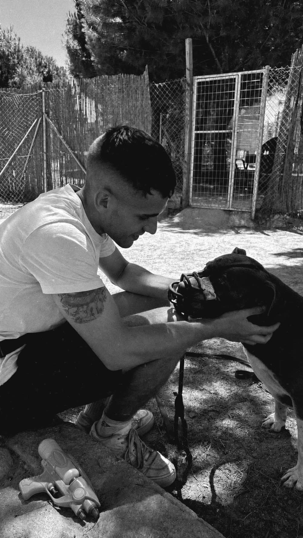 Adrián Teruel agachado, sujetando con calma la cabeza de un perro con bozal